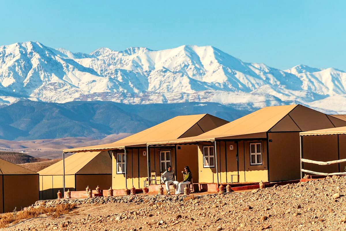 Row of desert tents in Agafay with the snowy Atlas Mountains behind