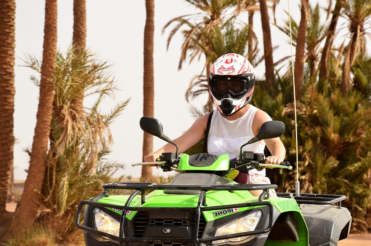 Lachende rijder op een groene quad tussen palmen